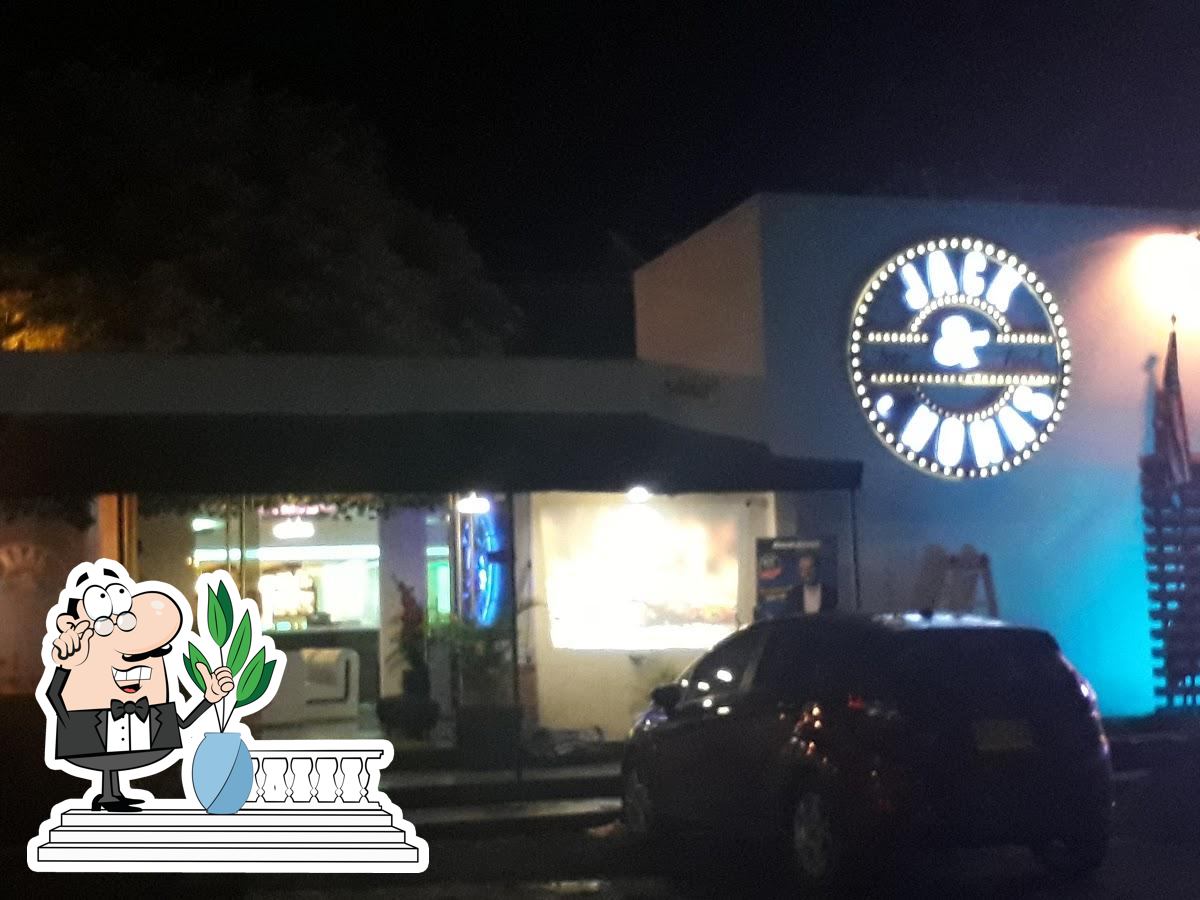 Fachada de Jack & Jhonas de noche con el logo circular iluminado
